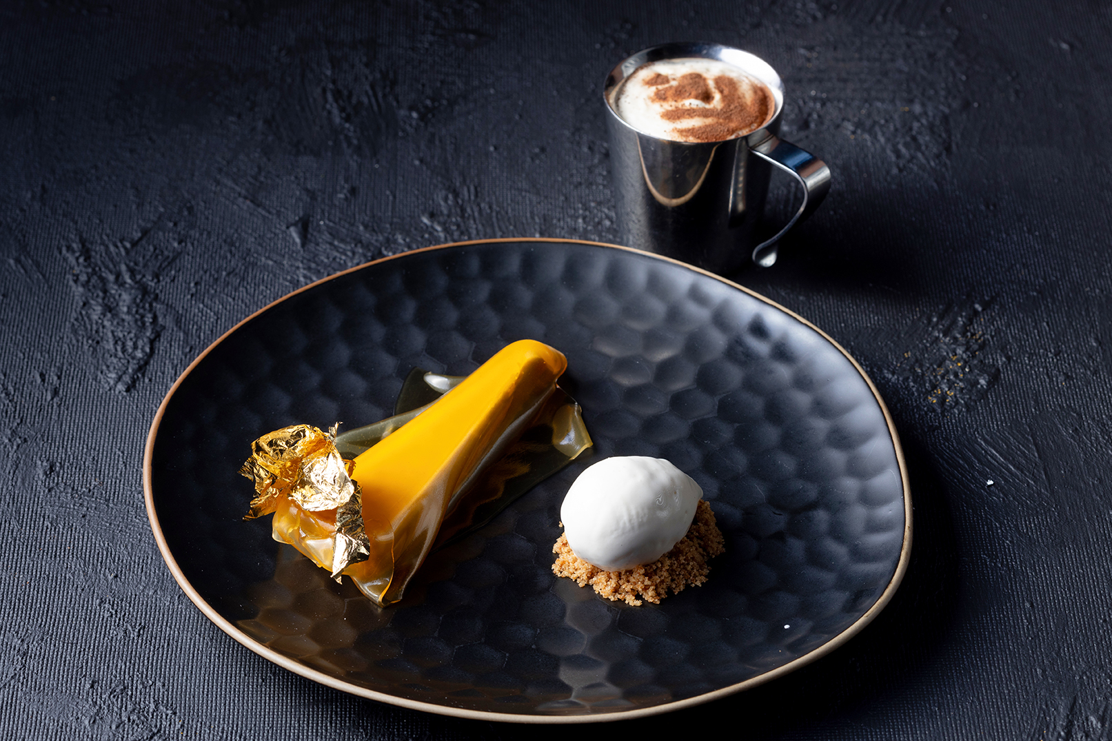 Dessert course with citrus and cream on a dark plate